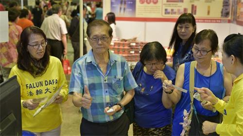 '图3:来宾在了解到法轮功的信息后,竖起大拇指表示肯定。'