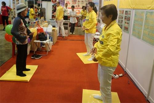 '图8:李女士跟着法轮功学员学炼第二套功法。'
