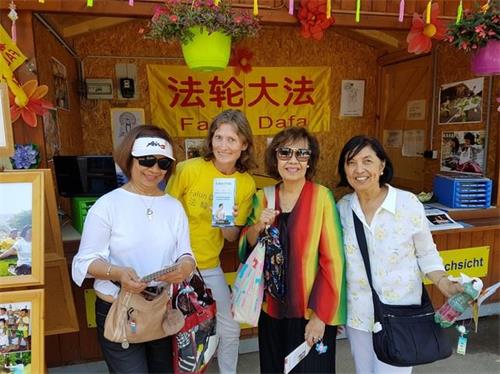 '图2:三位游客觉得法轮功炼功音乐非常祥和,她们拿取了真相资料。'