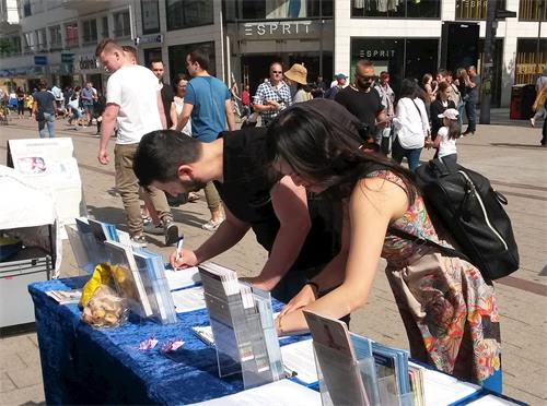 '图5~8:为了帮助制止在中国发生的强摘器官罪行,路人在征签表上签名。'