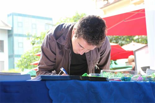 图3:了解真相后,这位年轻人签名支持法轮功学员制止迫害。