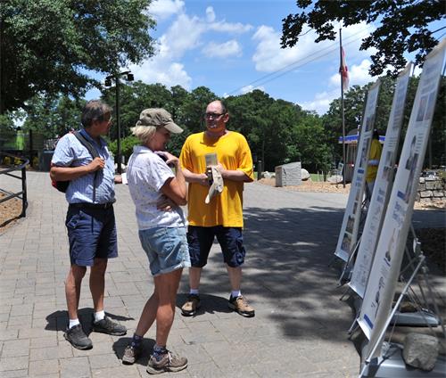 图5: 2019年6月30日,来自乔治亚州纽南(Newnan)市的Lee Hall女士与Kevin Hall先生,在真相展板前凝听法轮功学员的介绍。