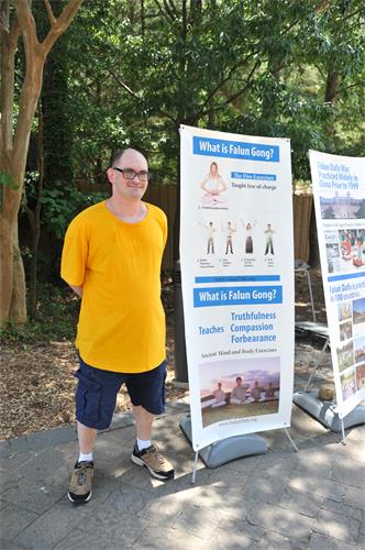 图7:2019年6月30日,法轮功学员Cody Scholberg在石头山脚的真相展板前留影。