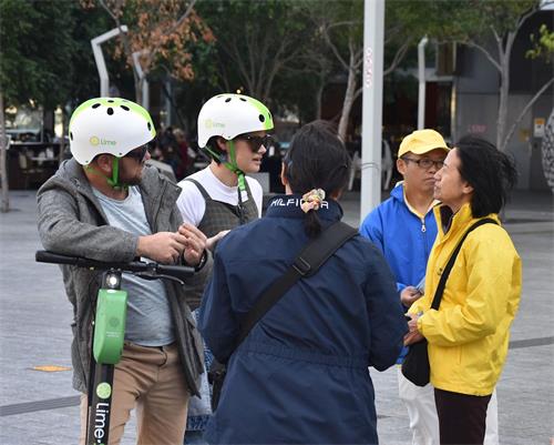 '图5:大学艺术系学生阿曼达(左二)和同伴安东尼(左一)在听法轮功学员讲述迫害'