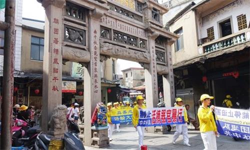 '图2:法轮功学员手持“制止中共非法活摘器官暴行”等横幅,行经邱良功母节孝坊。'