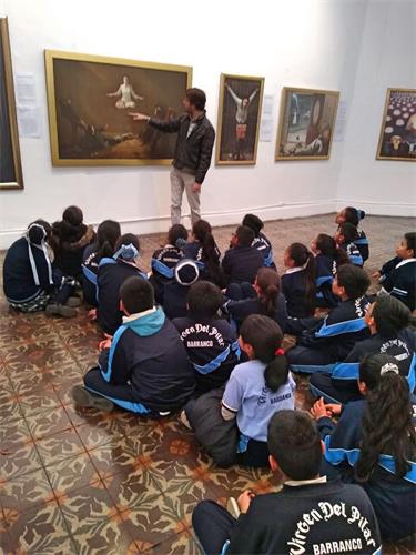 '图3:当地学校带学生集体前来观看画展,听学员解说每幅画的内涵。'