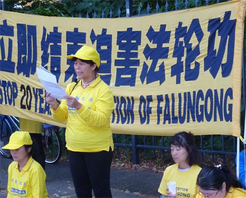 '图8:法轮功学员鲍学珍女士在中共驻丹麦使馆前介绍她被非法判刑关押期间几乎被活摘器官的经历'