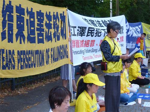 '图9:法轮功学员魏再群女士在中共驻丹麦使馆前讲述因为修炼法轮功,国内亲人家破人亡,她自己在丹麦遭受中使馆报复迫害的经历'