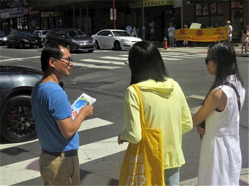 '图4:两位年轻华裔在了解法轮功是什么'