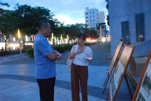 '图9:法轮功学员徐小姐向看真相展板的游客解释'
