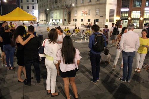 '图1~2:法轮功学员在七月十九日晚烛光守夜 ,吸引许多路人的关注。'