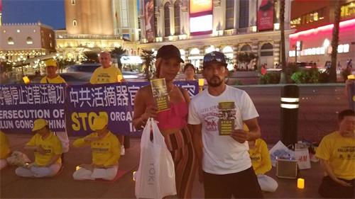 '图10:做某网站行政管理工作的乔安娜(Joannna)女士拿着真相传单,站在横幅前留影纪念'