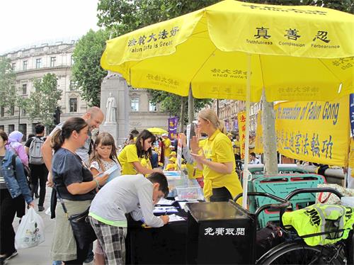 '图13:二零一九年七月二十日,在伦敦圣马丁广场,从匈牙利布达佩斯来伦敦旅游的律师拉维亚(Lavia)一家四口签名支持法轮功反迫害'