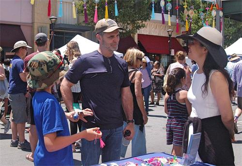 '图8~10:游行结束后,人们来到法轮功的摊位进一步了解法轮功。'