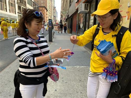 '图4:韩裔民众很高兴接过法轮功学员赠送的小莲花。'