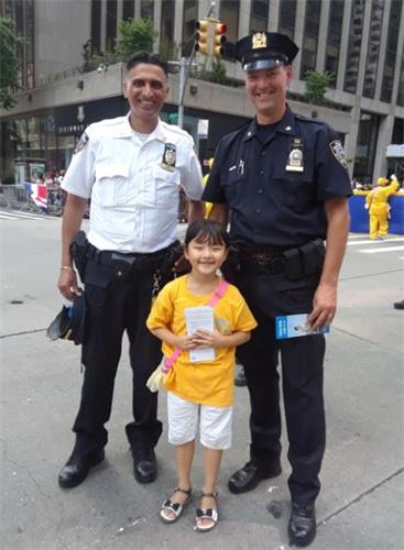 '图5:维护治安的警察接过法轮功小弟子发给的传单,并高兴地与之合影。'