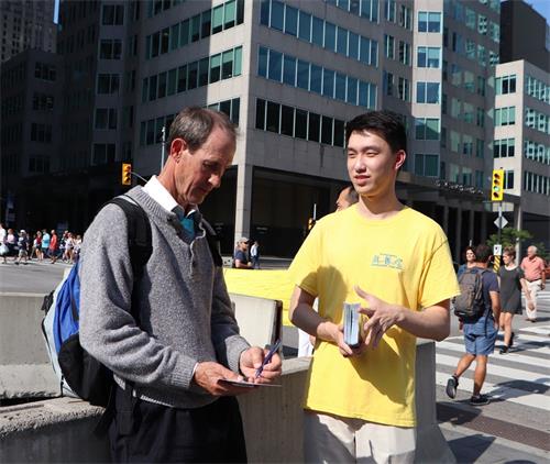 '图9:出生在加拿大在澳大利亚工作的凯文·斯塔尔斯(Kevin Stalls)表示非常支持法轮功学员反迫害。他正在“停止迫害法轮功”的明信片上签名。'