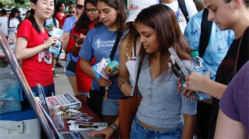 '图2:来往的学生们纷纷驻足了解大法学生社团'