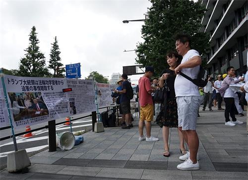 '图6~7:日本法轮功学员在东京九段下车站摆展板,讲真相,民众驻足阅读展板。'