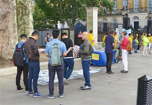'图7:一群大陆年轻人在跟法轮功学员交谈并观看展板和资料,图为唐宁街十号首相府对面。'
