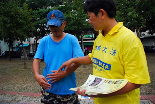 '图8:文化公园里,一位市民认真观看功法展示,他现场学功,后来还参加了九天学法炼功班。'