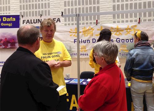 '图1:法轮功学员向参观民众介绍功法'