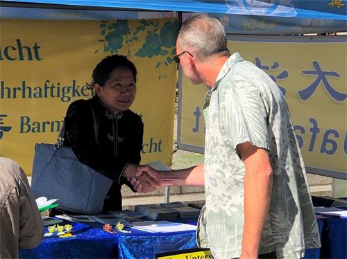 '图6:一位签了名反迫害的市民(右)与法轮功学员握手表示感谢'