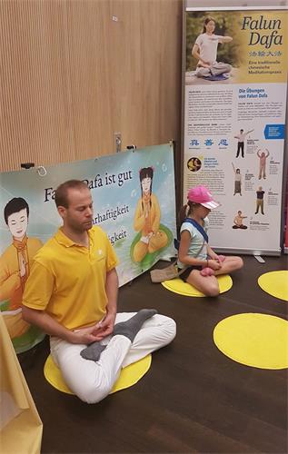 '图3:去年在健康展上学过功的孩子(右),再次看到法轮功,马上坐下和学员一起打坐。'