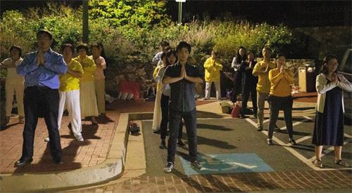 '图6:夜幕降临,法轮功学员在中使馆外静静地炼功。'