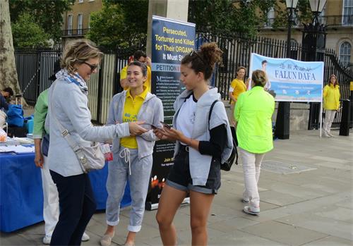 图1:英国学员卡琳娜‧德珀利安(Carina Depelean,中)在跟游客讲述法轮功的真相。