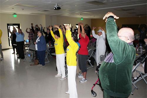'图2:分会负责人巴蒂先生(右一)专注学功,已经了解到法轮功使人身心受益'