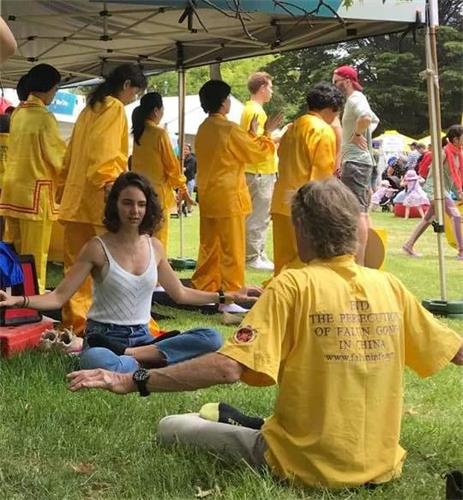 '图6~8:澳洲国庆日当天市中心举办大型游园会,介绍法轮大法的展位上学员们不间断的展示五套功法,现场有不少民众学炼。'