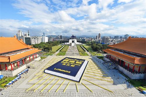 '图1:二零一八年十一月二十四日,约五千四百名法轮功学员于台北自由广场排出巨幅的英译本《转法轮》:深蓝色的书皮、金黄色的书名与作者名、白色的书页,并绽放四十二道金黄色的光芒,场面壮观殊胜。'