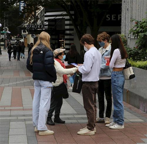 '图10:学员向路人讲真相,一组民众驻足集体签名'
