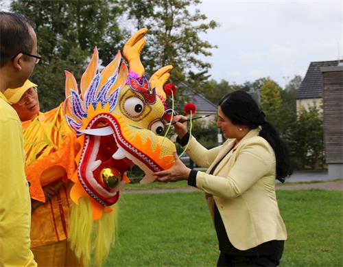 '图3:移民专员阿德米博士在为法轮功学员舞动的金色祥龙画龙点睛'