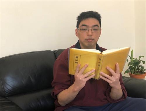 '图2:墨尔本法轮功学员爱默斯(Amos)在阅读法轮功的主要著作——《转法轮》。'