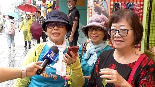 '图5~6:很多游客争先拿取印有“法轮大法好、真善忍好”的精美莲花纪念品,得到莲花的民众欣喜雀跃,彷若拿到吉祥如意的护身符,连连称谢。'