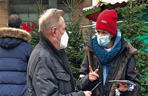 '图5:法轮功学员在讲述真相,这位男士(中)在认真倾听。'