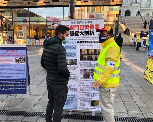 '图7:一位路人在展板前听法轮功学员讲真相'