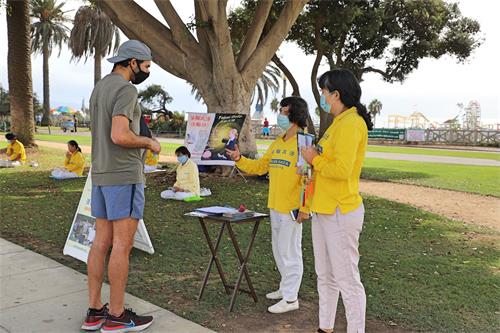 '图3:法轮功学员跟这位年轻人迈克(Mike)讲述中共迫害法轮功的真相。'