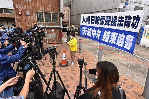 图2: 法轮功学员代表周胜在写有“人权日跨国声援法轮功”、“天灭中共 结束迫害”的横幅前发言,有众多媒体到场。