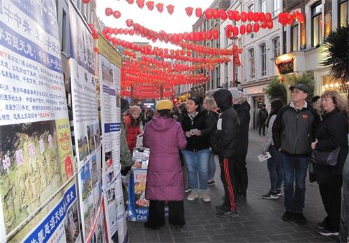 '图6:二零二零年二月一日,从剑桥来伦敦游览的苏珊(Susan)和伊恩(Inn)夫妇(图右正在观看展板两人)在伦敦唐人街驻足了解法轮功真相'