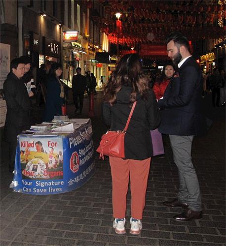 '图9:二零二零年二月一日,在伦敦工作的罗马尼亚人迈克尔(Michael,最右边站立者)在伦敦唐人街驻足了解法轮功真相并签名支持法轮功学员反迫害。'