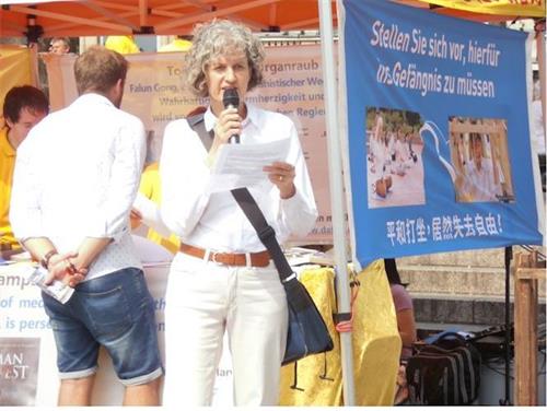 '图:德国北威州旅游胜地科隆大教堂广场上的法轮功学员集会中,碧尔姬特发言揭露中共迫害。'