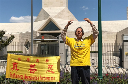 '图8:二零二零年五月十三日,在法轮大法洪传二十八年的这一天,谢维穿上印有“法轮大法好”的黄T恤,来到中共驻美国大使馆前炼功,与全世界的大法弟子一起庆祝法轮大法日。'