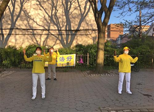 '图:二零二零年五月十三日,这几位居住在纽约布鲁克林的法轮功学员在一华人超市对面的小操场上炼功庆祝大法日。有西人拍照并拿了英文传单和小莲花。'