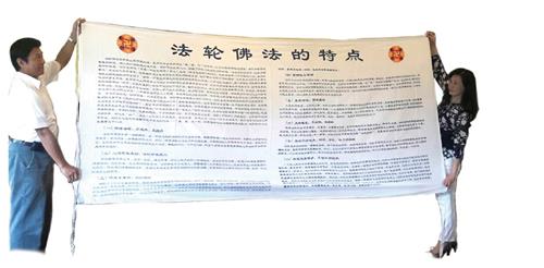 '图3:张震宇与妻子展示保存完好的舅舅一九九五年从贵州带来的“法轮佛法的特点”横幅。(博大出版社提供)'