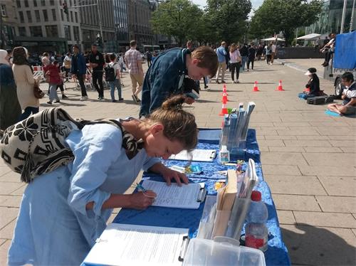 '图15:来自贝吉施格拉德巴赫(Bergisch Gladbach)的萨拉(Sarah)直接在到信息台前签名反迫害。'