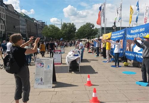 '图17:一位女士为法轮功学员的信息日活动拍照留影并签名支持法轮功学员反迫害'