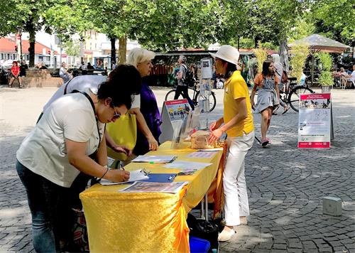 '图4~5:法轮功学员在慕尼黑居民区红十字广场(Rotkreuzplatz)举办讲真相活动'